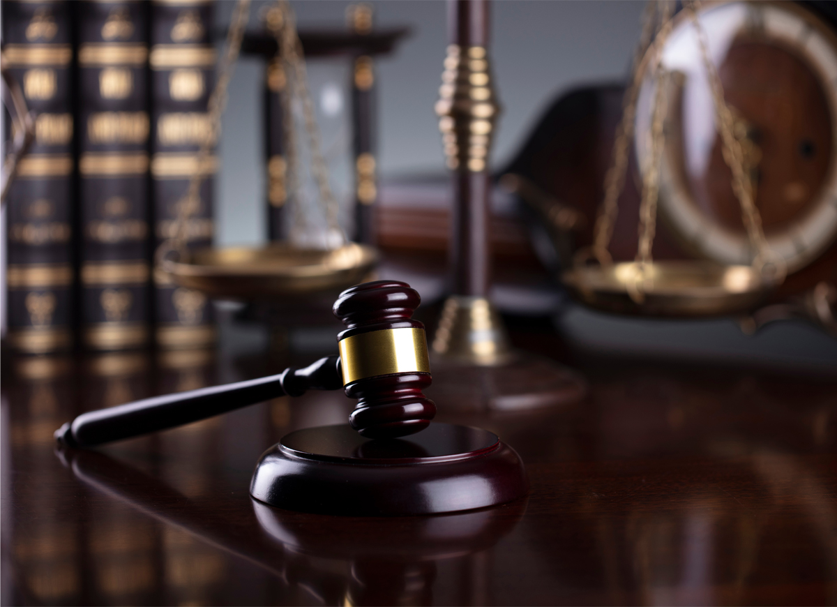 Gavel on a Desk with Law Books and Scales of Justice in Background